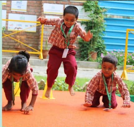 Activité sportive en plein air à la Lotus Petal Senior Secondary School Three children in sports kit take part in an outdoor physical activity in the school playground.